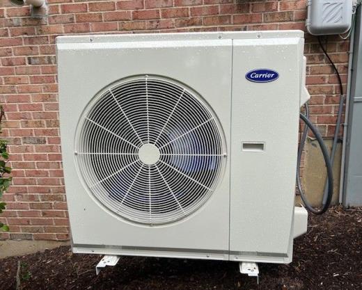 Carrier outdoor heat pump installed by Air-Rite beside a brick home
