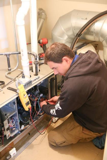 Air-Rite technician testing furnace wiring with a meter in a customer's home